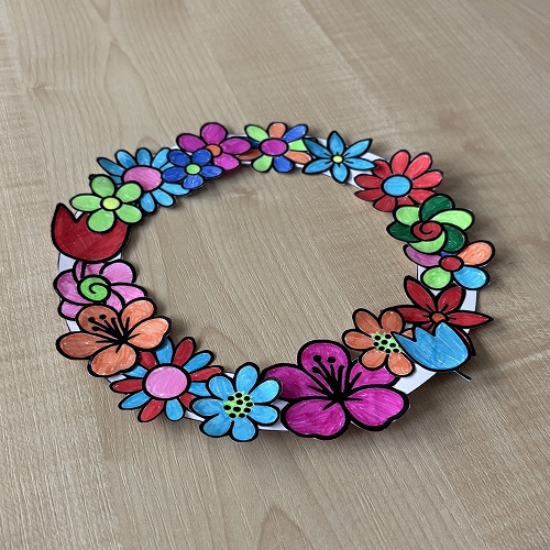 Färdigt pyssel ligger på ett bord - en blomkrans som målats med tuschpennor.